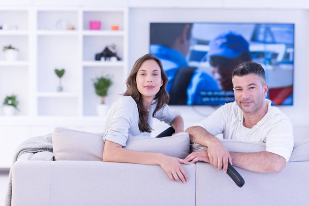 Young couple on the sofa watching television - Фото, изображение