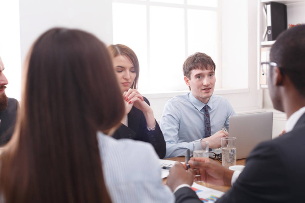 Reunión de negocios. Jóvenes empleados exitosos escuchan comentarios en el escritorio de la oficina
 - Foto, imagen