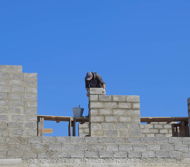 The builder builds the wall of the house from the cinder block. Worker at the construction site. - Foto, Bild