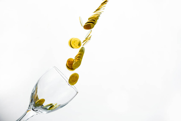 Golden coins splash in a glass of champagne on the wall backgrou - Foto, afbeelding