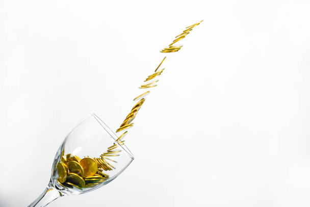 Golden coins splash in a glass of champagne on the wall backgrou - Foto, Bild