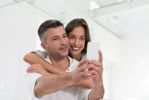 happy couple using mobile phone at home - Photo, Image
