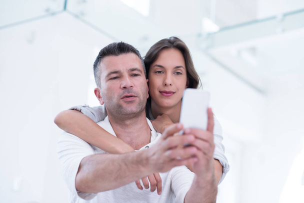 happy couple using mobile phone at home - 写真・画像