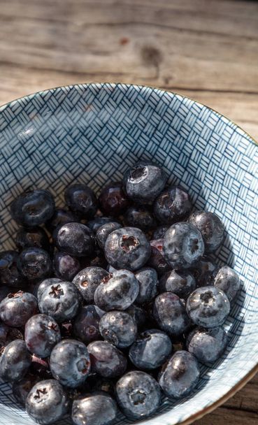 Organic blueberries in a blue and white bowl - Valokuva, kuva