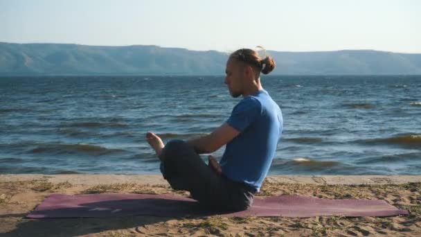 молодой человек в медитации у океана, горы на заднем плане
 - Кадры, видео