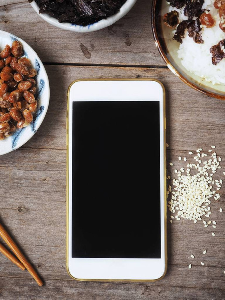 Smartphone i natto z gotowanego ryżu i wodorostów na podłoże drewniane - Zdjęcie, obraz