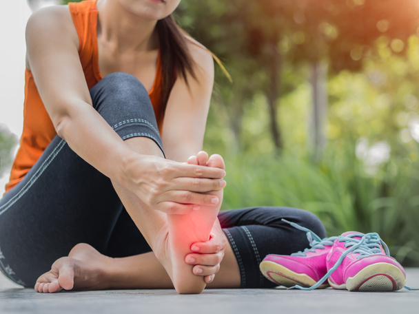 Mujer de enfoque suave masajeando su doloroso pie mientras hace ejercicio
.    - Foto, Imagen