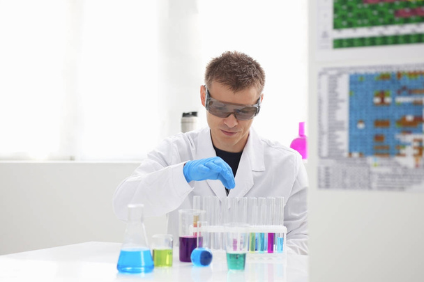 Un chimico maschio tiene in mano una provetta di vetro trabocca di una soluzione liquida
 - Foto, immagini