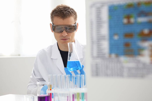 Un chimiste masculin tient dans sa main un tube à essai en verre débordant d'une solution liquide
 - Photo, image