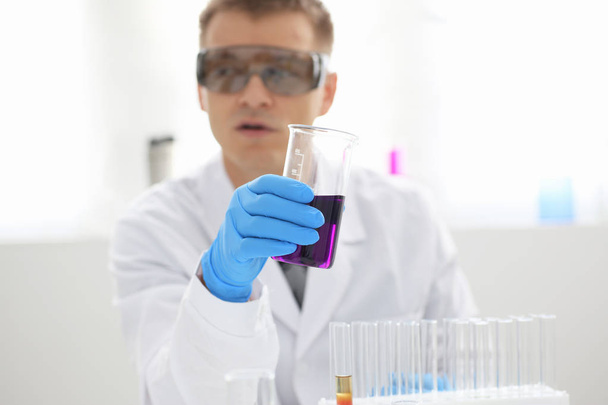 Mies kemisti pitää koeputki lasia kädessään ylivuotaa neste ratkaisu
 - Valokuva, kuva