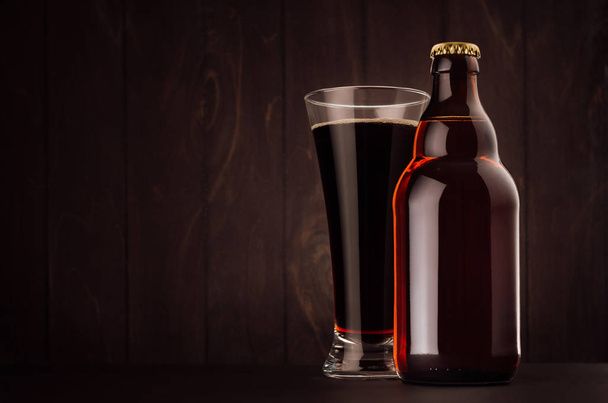 Brown beer bottle belgian steinie and glass pilsner with porter on dark wood board, copy space, mock up. - 写真・画像