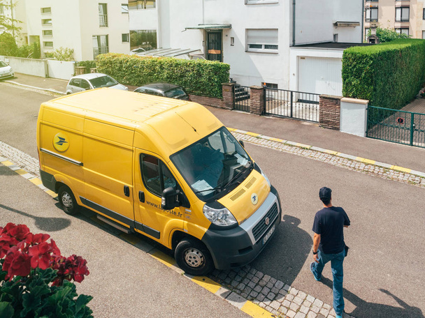 Man courier walking toward la Poste yellow delivery van - Foto, immagini