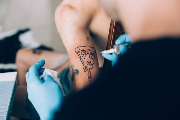 Hipster man gets pizza tattoo - Foto, afbeelding