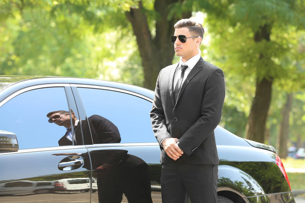 Handsome bodyguard near car outdoors - Foto, imagen