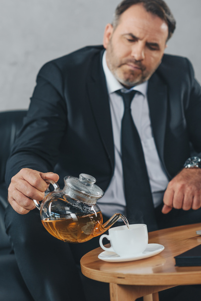 businessman pouring tea into cup - Foto, afbeelding