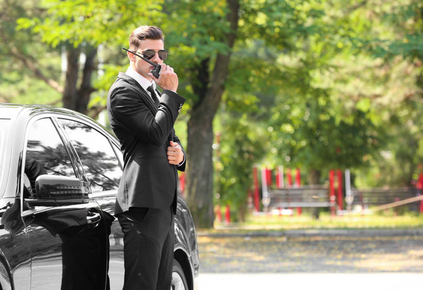 Handsome bodyguard near car outdoors - Photo, image
