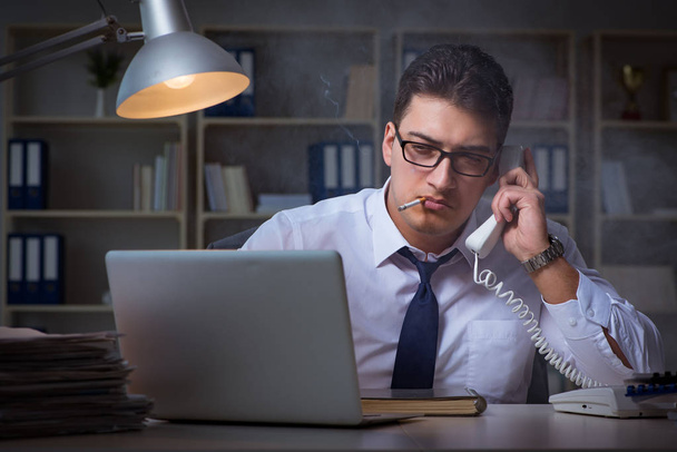 Бизнесмен говорит по телефону и курит в офисе - Фото, изображение