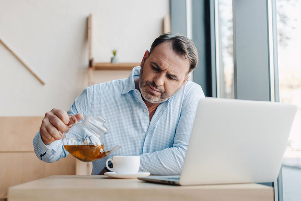 businessman pouring tea into cup - Foto, afbeelding