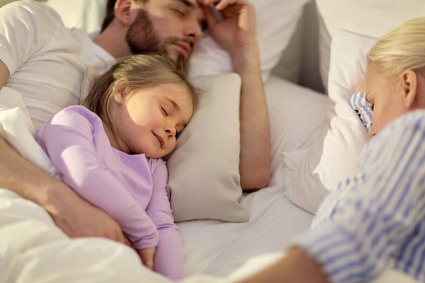 Familia feliz durmiendo en la cama en casa
 - Foto, imagen