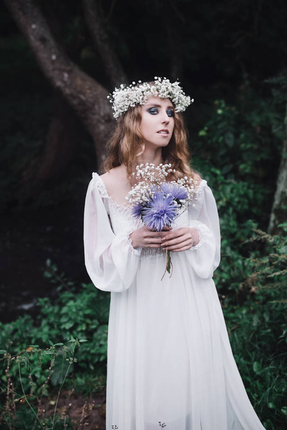 schöne Mädchen in einem weißen Kleid in einem dunklen Wald. - Foto, Bild