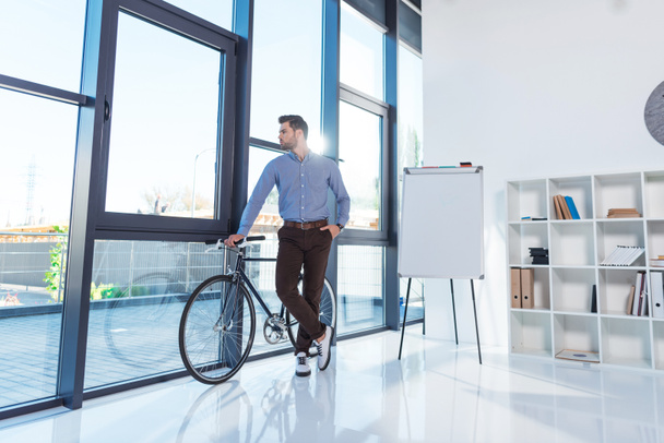 бізнесмен з велосипедом в офісі
 - Фото, зображення