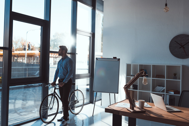 businessman with bicycle in office - Фото, зображення