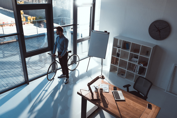 Empresario con bicicleta en oficina
 - Foto, imagen