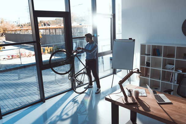 businessman with bicycle in office - Zdjęcie, obraz