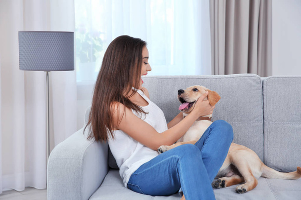 Young woman resting with yellow retriever at home - Photo, Image