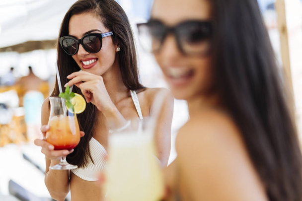 women on beach enjoying cocktails - Фото, зображення