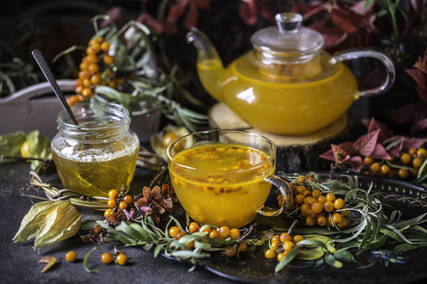 tea with sea buckthorn and honey and autumn leaves - Фото, изображение
