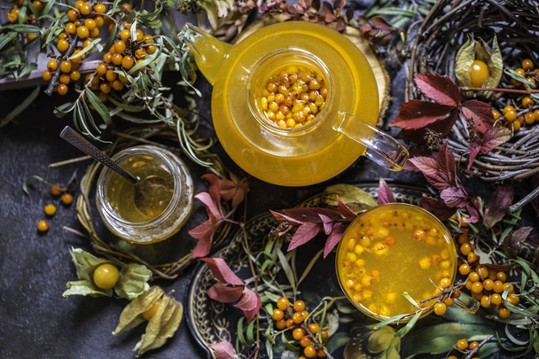 tea with sea buckthorn and honey and autumn leaves - Foto, afbeelding
