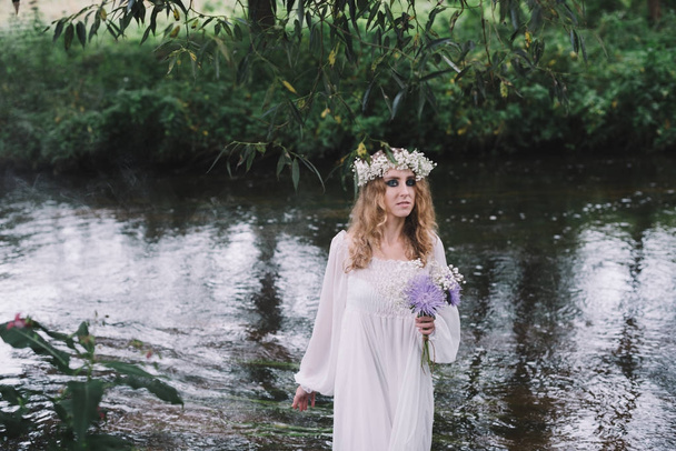 Belle fille dans une robe blanche près d'une rivière
. - Photo, image