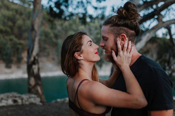 Hermosa pareja besándose en la naturaleza. Mujer sosteniendo su cabeza en las manos
 - Foto, imagen