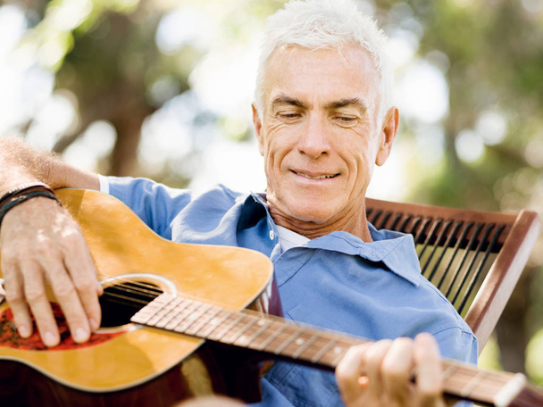 Senior man plying guitar outdoors - Foto, imagen