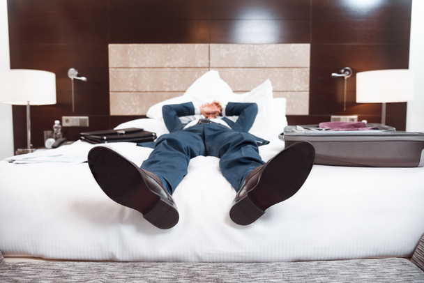 Väsynyt liikemies makaa sängyllä
 - Valokuva, kuva