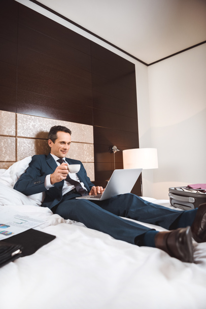 hombre de negocios en la cama con ordenador portátil y café
 - Foto, Imagen