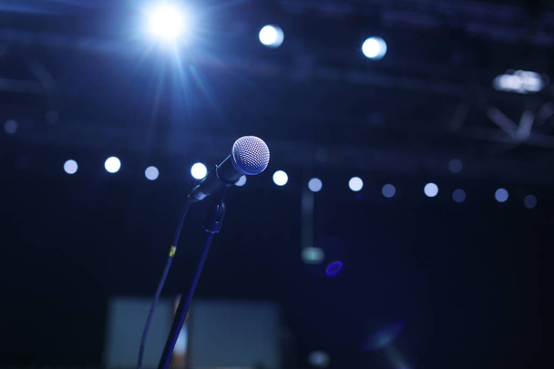 Close up of microphone in concert hall or conference room with cold lights in background. - Photo, image