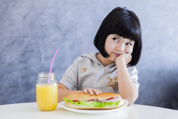 かわいい黒髪少女のサンドイッチを食べて - 写真・画像
