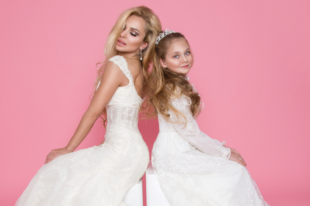 Mooie blonde vrouwelijke model, moeder met blonde dochter in jurken. Ze hebben prachtige trouwjurken - Foto, afbeelding