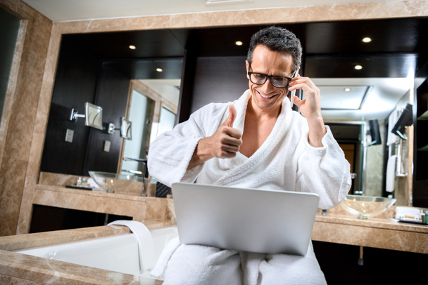 Businessman in bathrobe working with devices - Фото, изображение