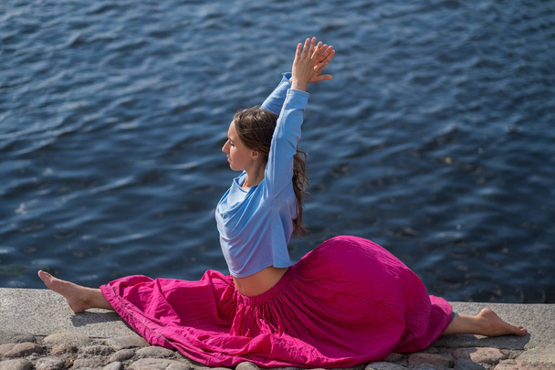 Sportowy sprawny kaukaski kobieta robi asan hanumanasana pozie postawy w przyrodzie. - Zdjęcie, obraz