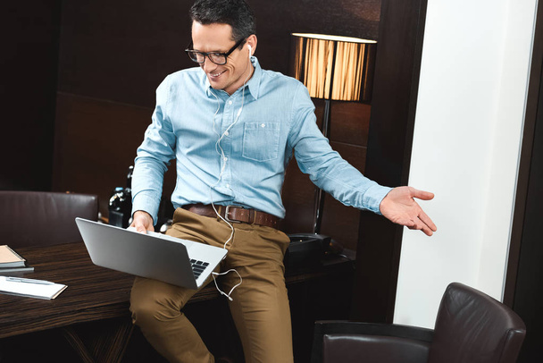 Smějící se podnikatel ve sluchátkách pomocí přenosného počítače - Fotografie, Obrázek