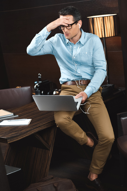 Laughing businessman in headphones using laptop - Foto, afbeelding