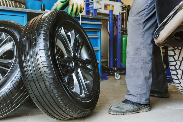 Mechanic changes car wheel in auto repair shop - Photo, Image