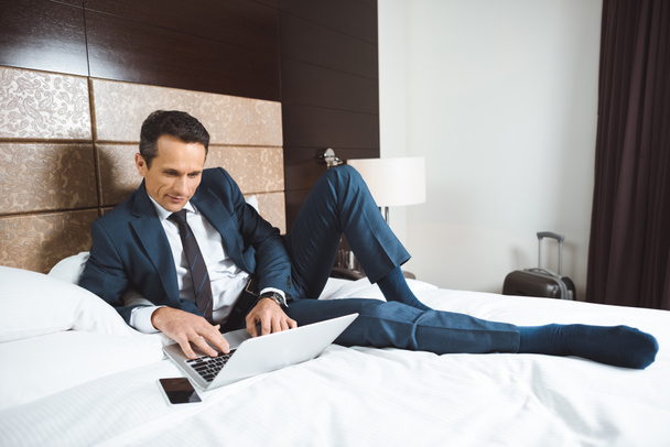 businessman on bed using laptop - Foto, afbeelding