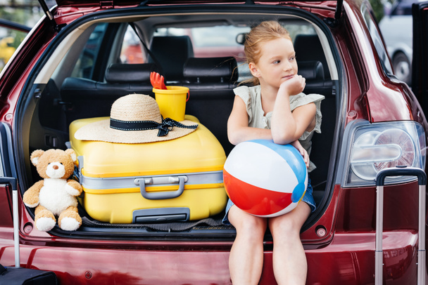 подорожуюча дівчина сидить у багажнику автомобіля
 - Фото, зображення