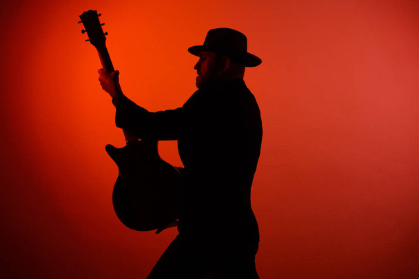 silhouette of a musician playing instrument in a hat - Photo, Image