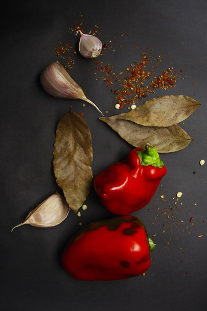 Красный сладкий перец с приправами и чесноком на сером фоне
 - Фото, изображение