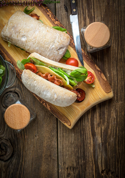 Ciabatta sandwich with arugula salad, bacon and yellow cheese. - Valokuva, kuva